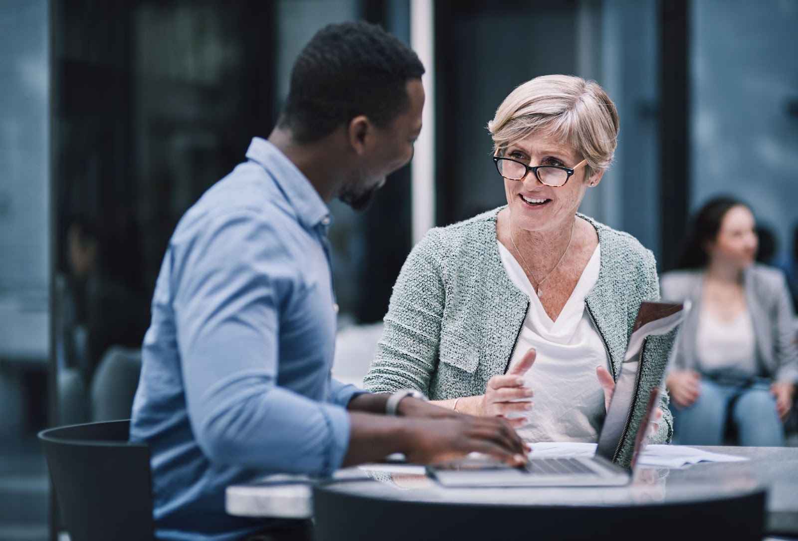 A man and woman discussing benefits of hiring a public adjuster at an outdoor table.