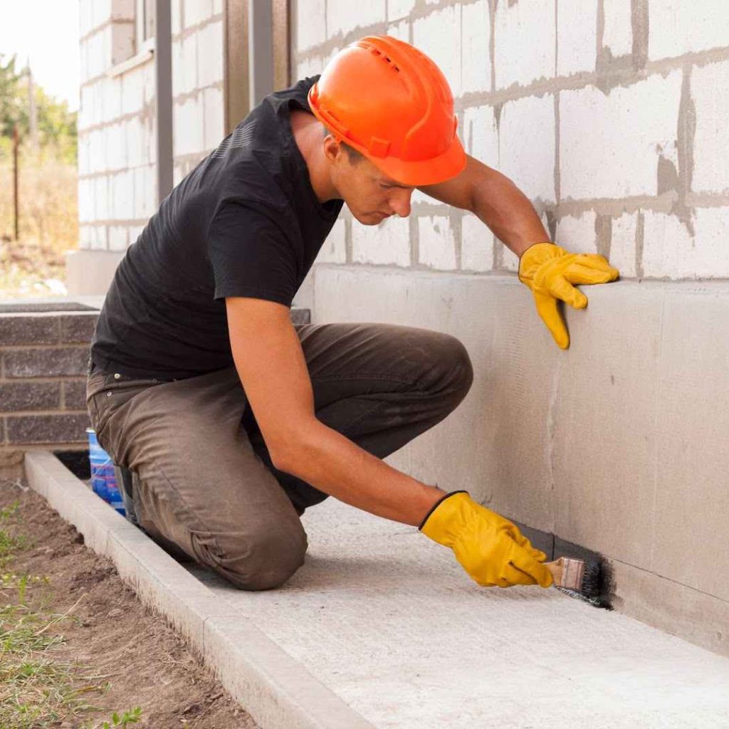 A man repairing a wall with cement due to foundation damage, foundation repair, and foundation problems.