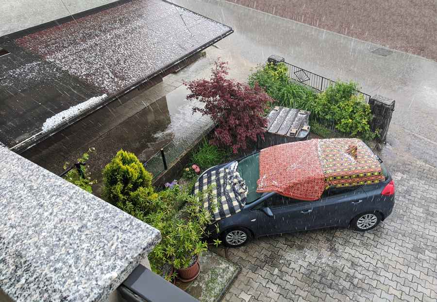 A car covered with a blanket sits parked in the rain, showcasing a moment of protection and care. Hudson Douglas Public Adjusters.