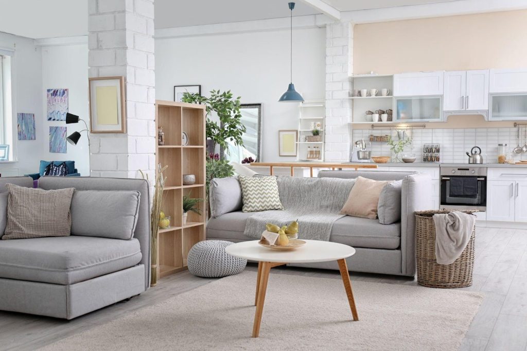 A cozy living room featuring a couch coffee table and an open kitchen area in the background