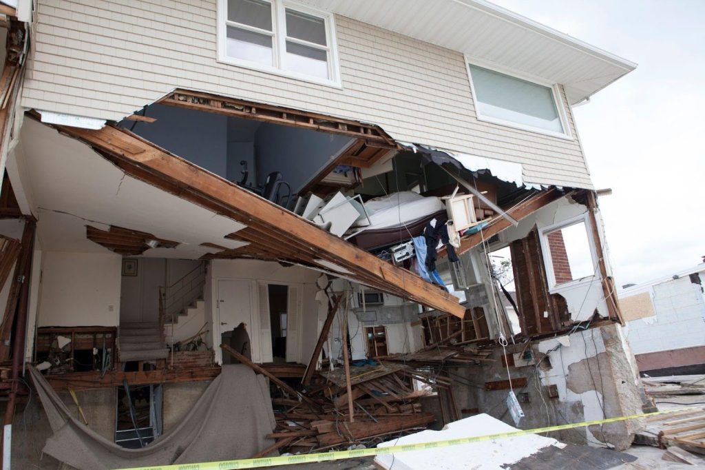 A house with broken windows and fallen debris from a hurricane